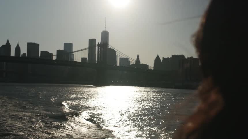 Woman on a boat viewing a city with the sun high in the sky