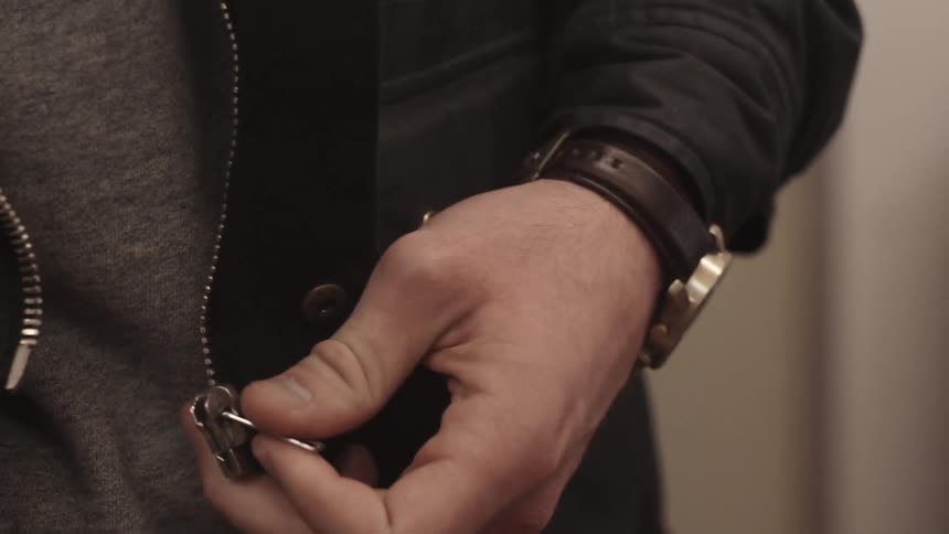 Man wearing a wristwatch zipping up his jacket