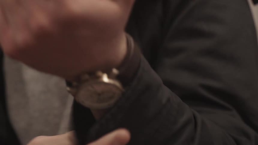 A man puts on a light jacket and snaps the cuff
