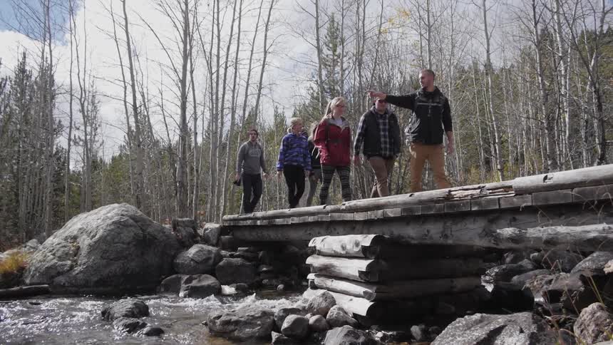 Group of people walk over a bridge in the wilderness