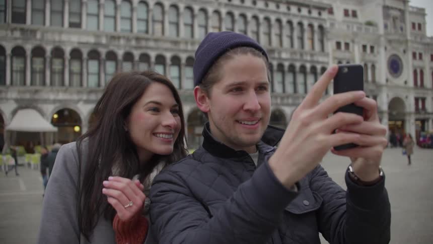 Man and woman taking a selfie outside in a city