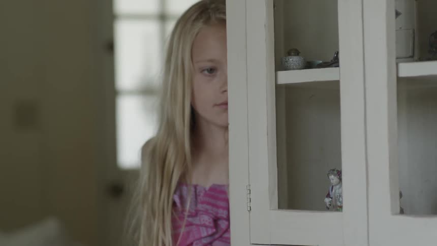 Young girl sadly looking around a hutch indoors