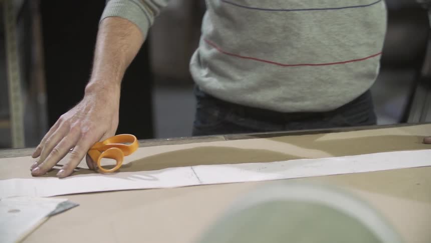 Person with scissors in hand adjusting brown paper