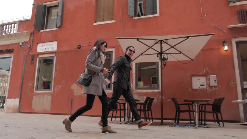 A man and woman walk next to a cafe