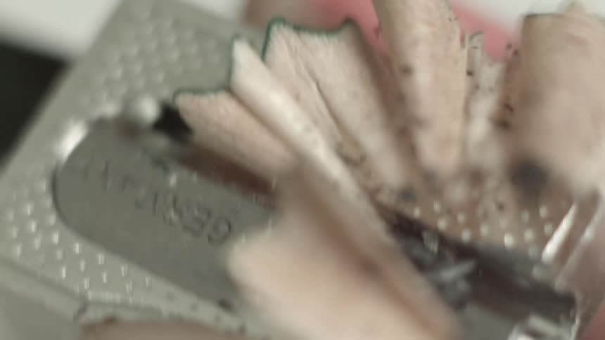 Metal sharpener being used to sharpen a pencil