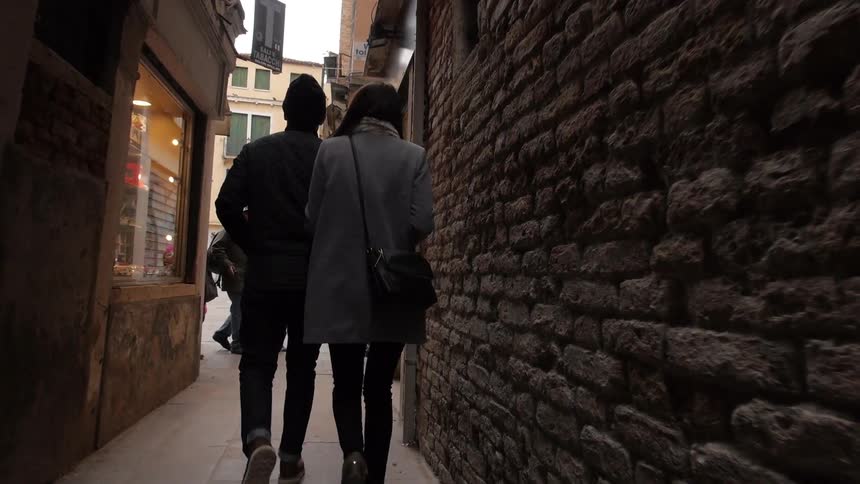 A couple walks through a narrow alleyway