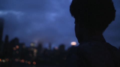 Person standing at sunset on a cloudy day by the city