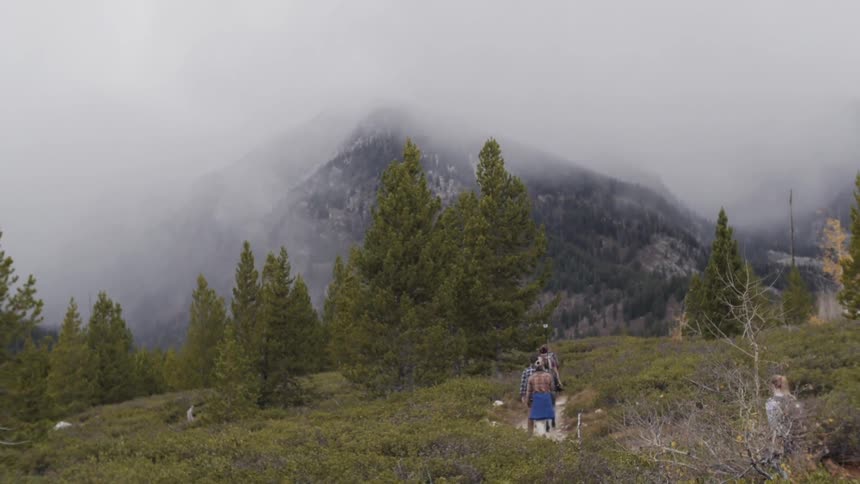 People hiking towards heavily fogged mountains