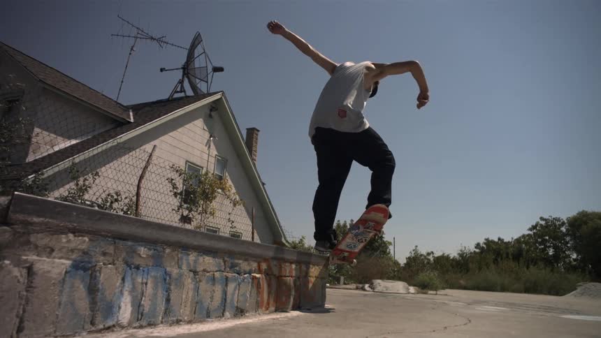 A man performs a skateboard trick off of a low ledge