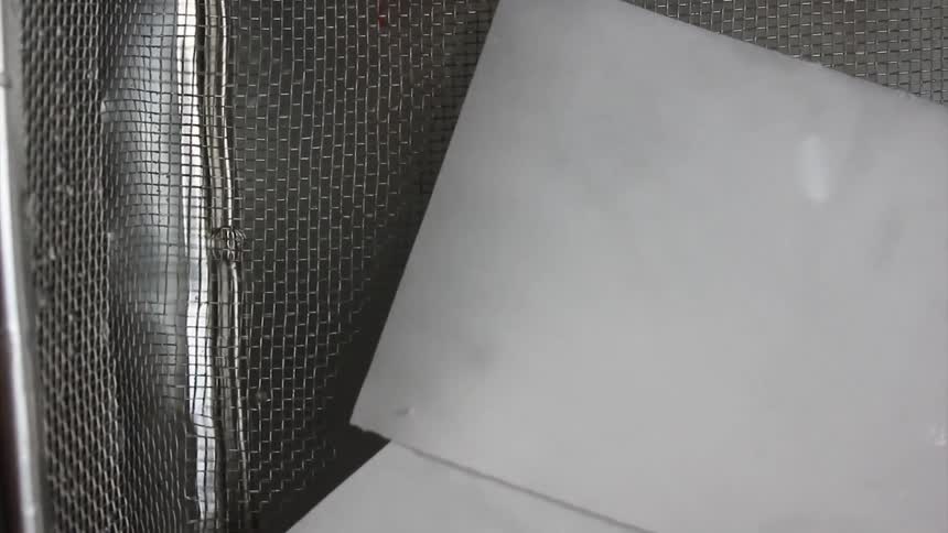 Sheets of paper are soaking in a mesh-walled container filled with a clear liquid