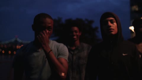 Four young men walk a city street at night