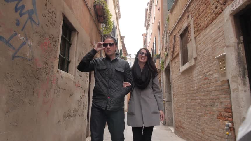 A man and woman walk down a narrow alley in the day