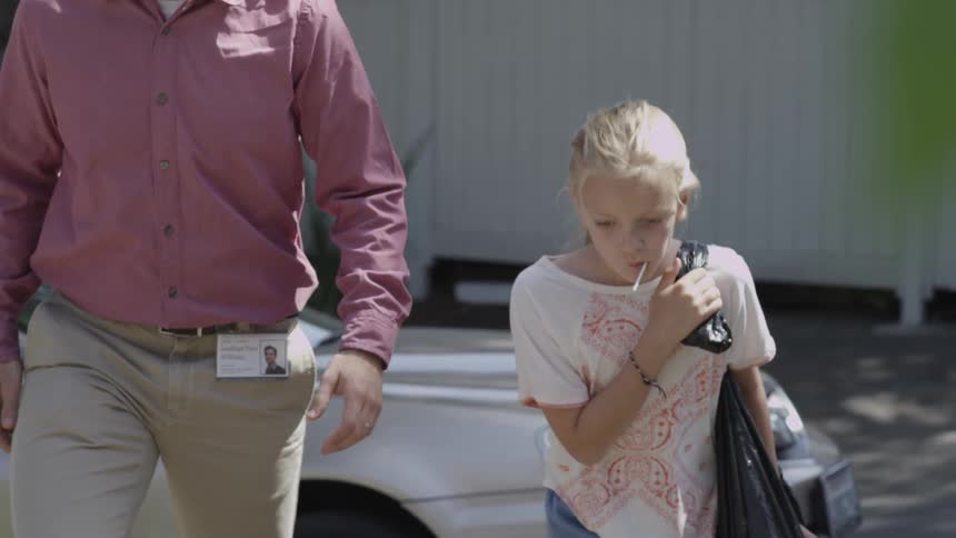 A man and a girl walk up a driveway with a car in the background