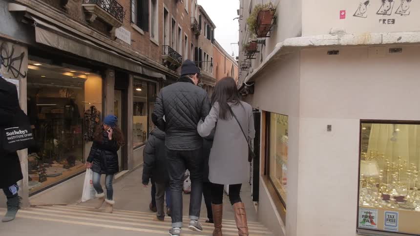 Busy town sidewalk with many people walking on a cloudy day