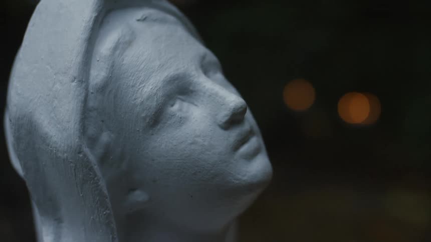 A white religious statue of a woman is looking up