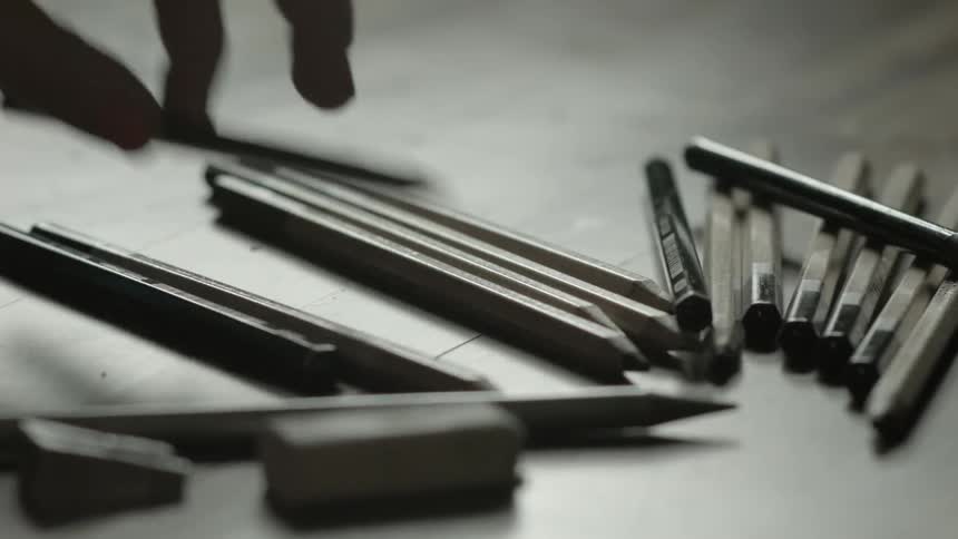 Row of writing instruments on a desk as some are picked up