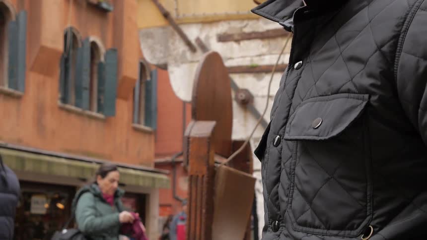 A man watches people passing on a city street