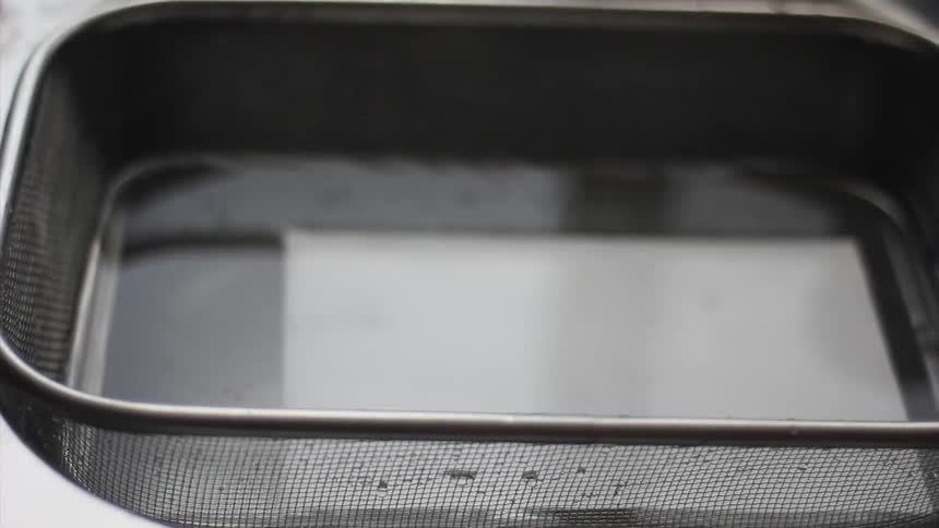 A man lifting film negative out of a tray of solution