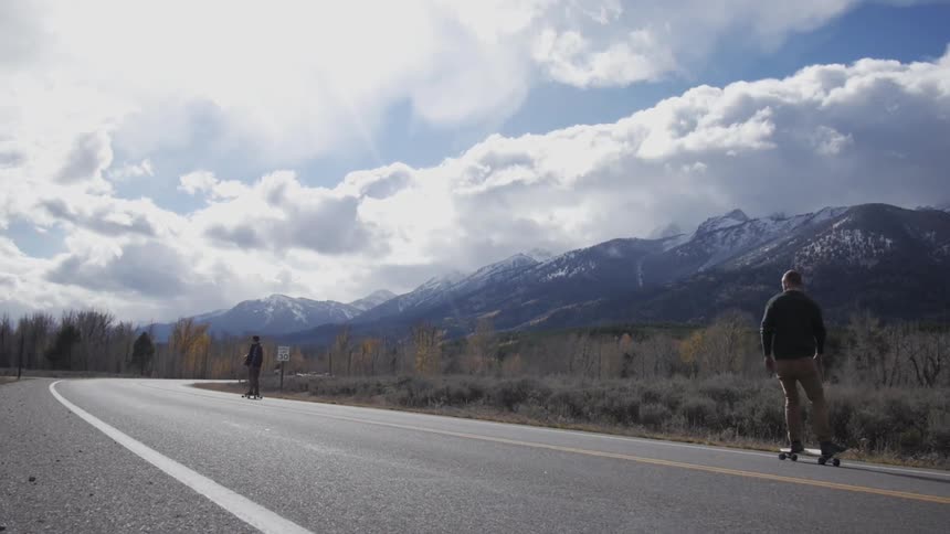 Cloudy day as a man rides his skateboard down a road