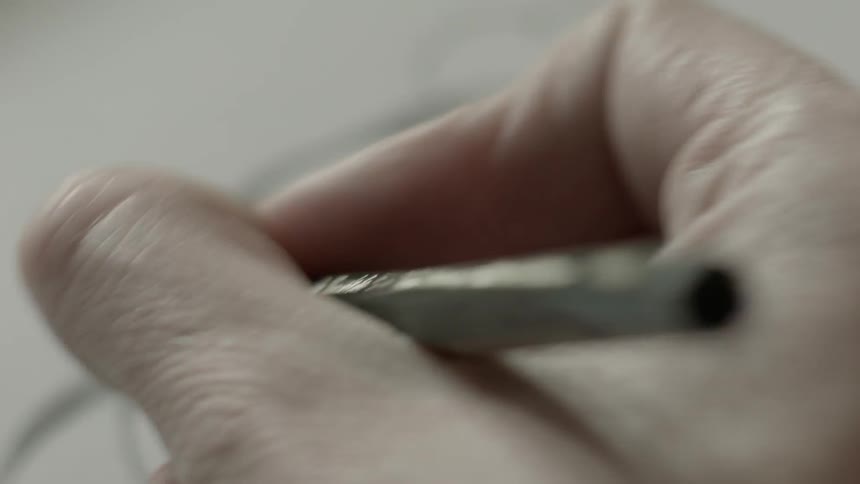 A hand sketches with a pencil