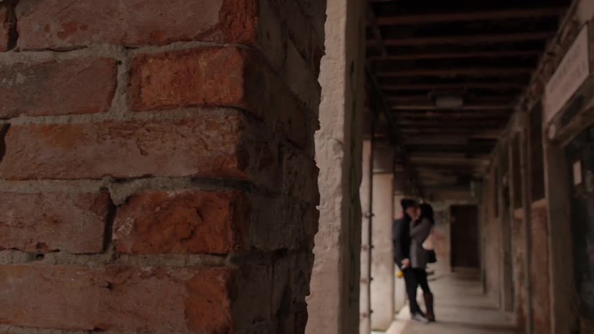 A man and woman kiss inside of a brick building