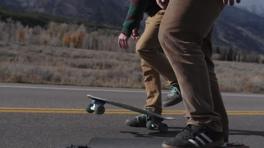 Two skateboarders skate next to each other