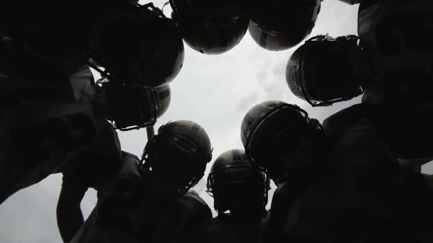 A football teams stands in a huddle