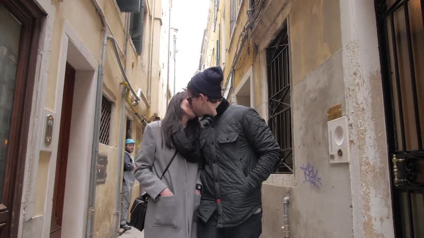 Man and woman walk down a narrow alley and kiss