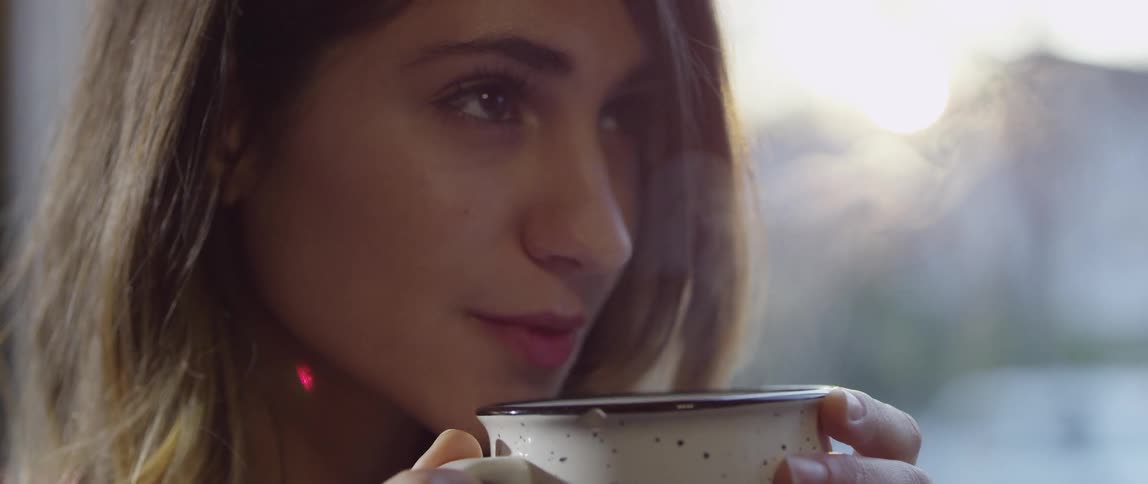 A woman smelling a steaming drink