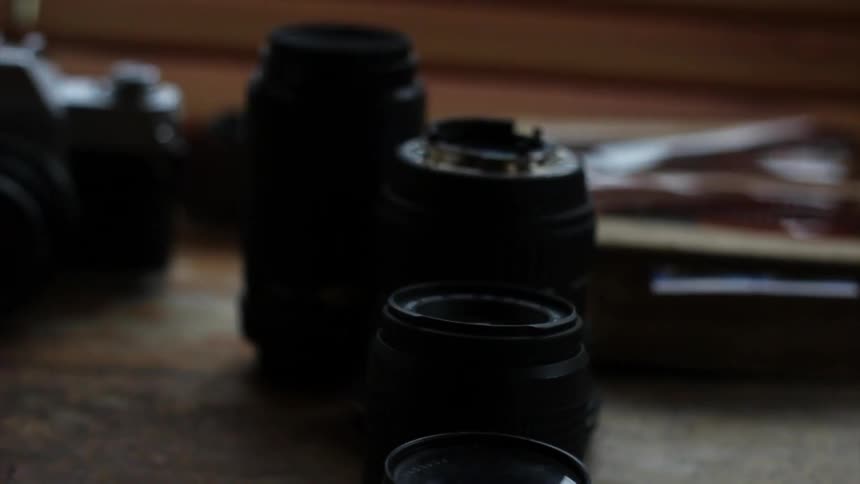 We move over camera equipment and lenses on a wooden table