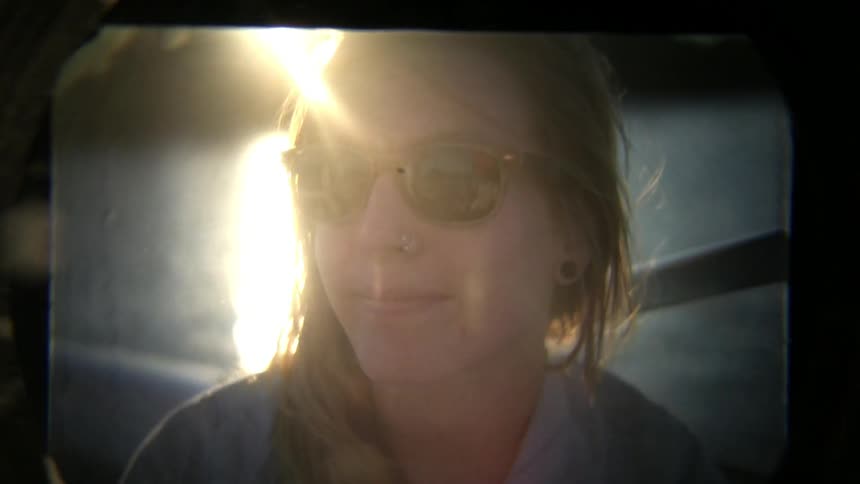 Film of a young woman smiling as water ripples behind her