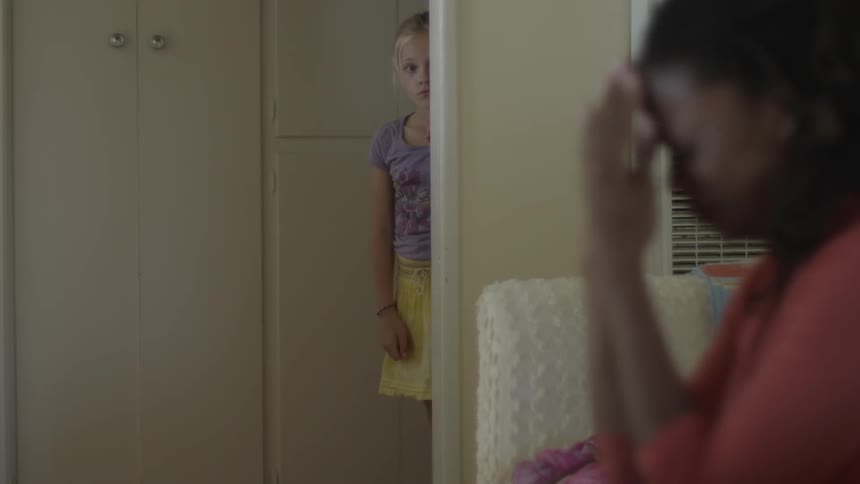 Young girl peeks out from behind the wall at woman