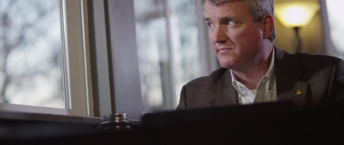 A man looking at something on his laptop and then turning to glance out of the window