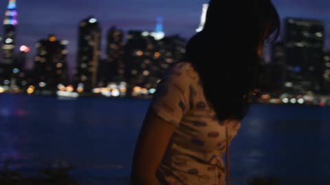 A woman looks at the skyline at night