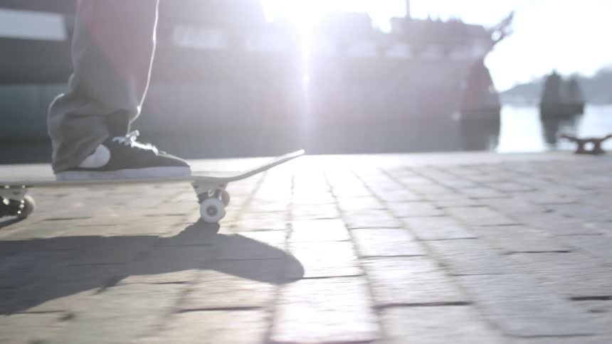 Man skateboarding on bricks by docks on a sunny day