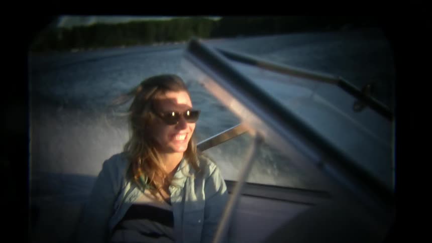 A woman smiles and laughs on a speeding boat