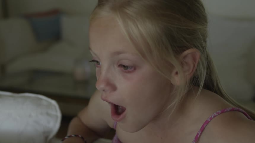 Girl leans over couch and looks surprised