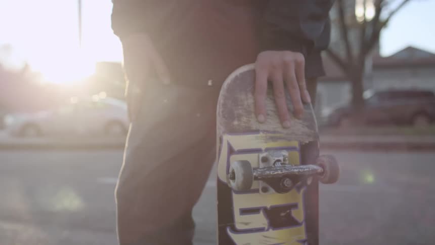 Man holding a skateboard on a sunny day
