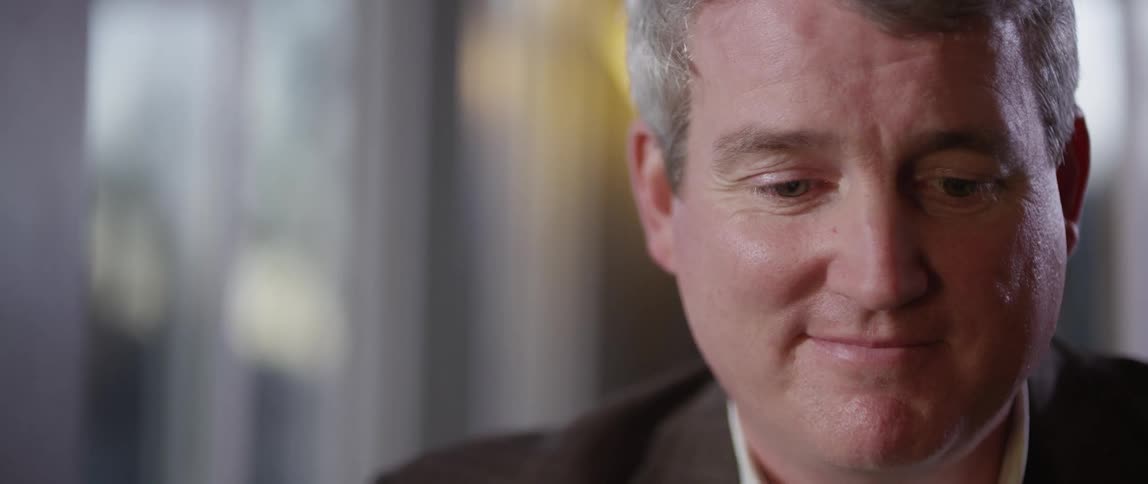 A middle aged man smiles quietly to himself