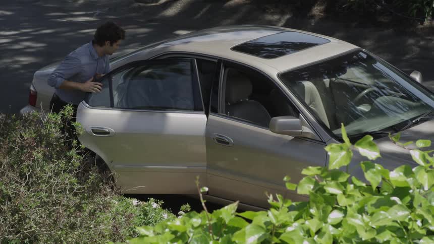 A man walking up to a car  and opening the back passenger side door