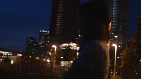 Woman standing outside at night near some buildings