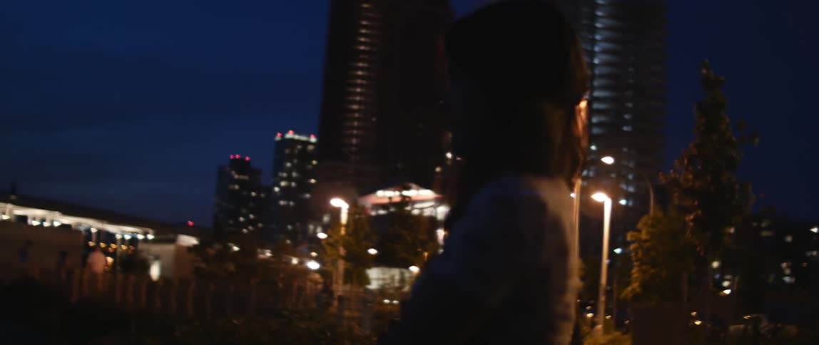 Woman standing outside at night near some buildings