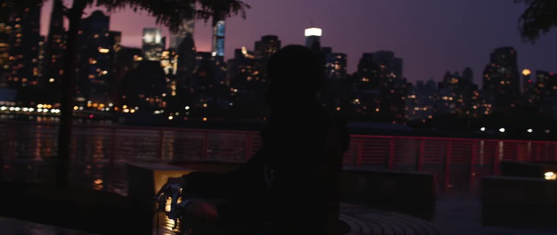 Person sitting on a bike at night time by the water