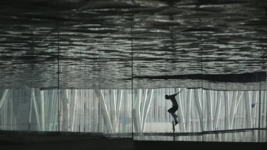 A silhouette of a man skateboards in the building