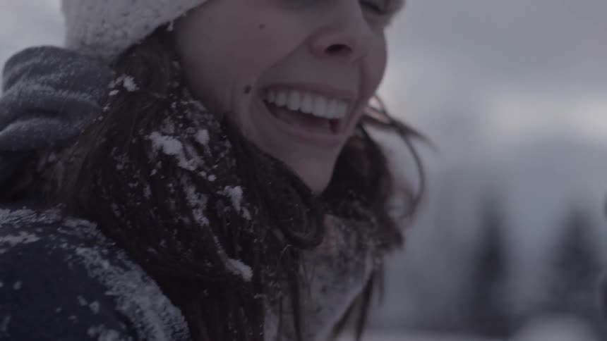 A woman is covered in snow smiling on a cloudy day