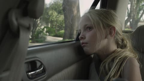 A little blond girl looking out of a car window