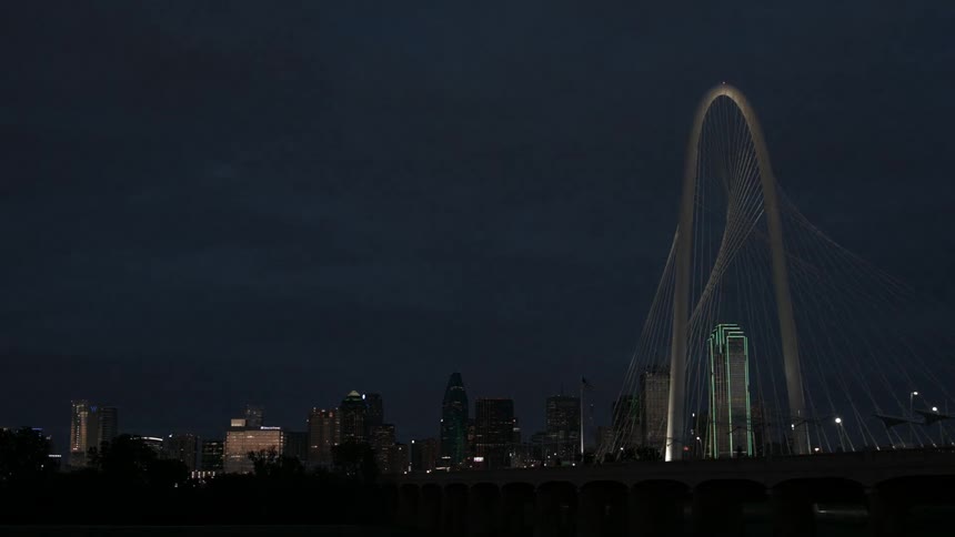 The large bridge leads to the brightly lit city at night