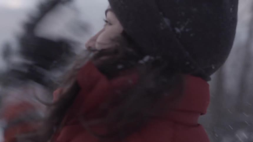 A young brunette woman smiling and turning to throw a snowball