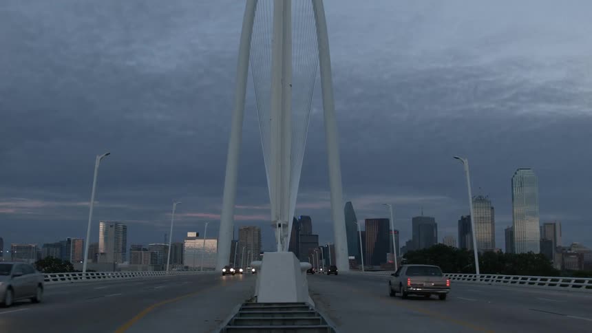 Timelapse of traffic on a bridge with a city skyline in the background at dusk