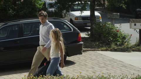 Man and girl walk down a driveway on a sunny day
